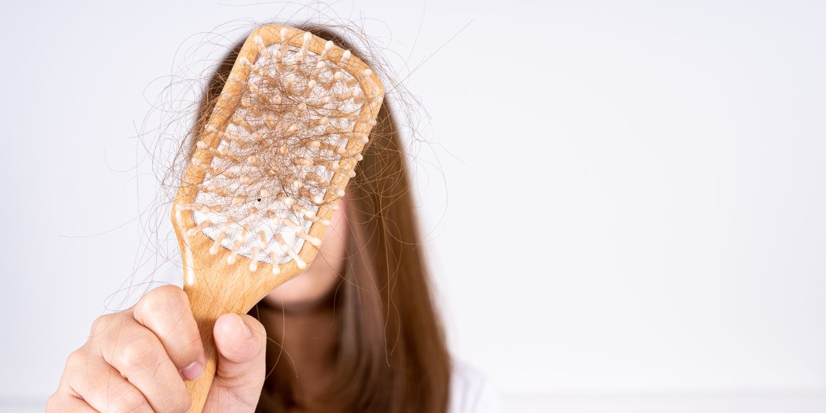 Una mujer muestra la caida del cabello en su cepillo